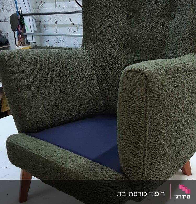 כורסה ירוקה עם ריפוד חסר על המושב